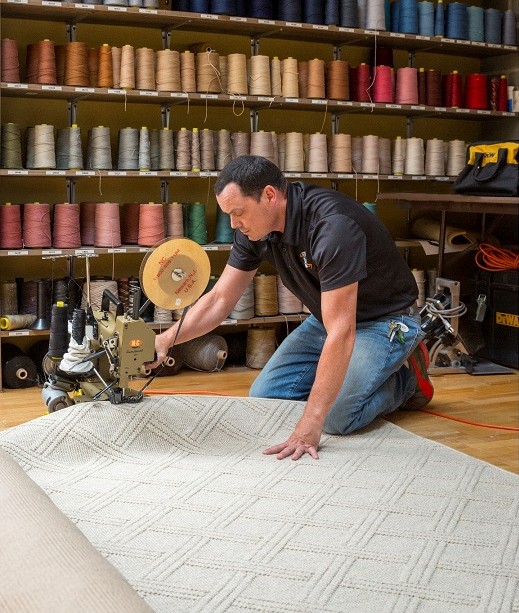 a man fabricating an off white rug with a diamond pattern